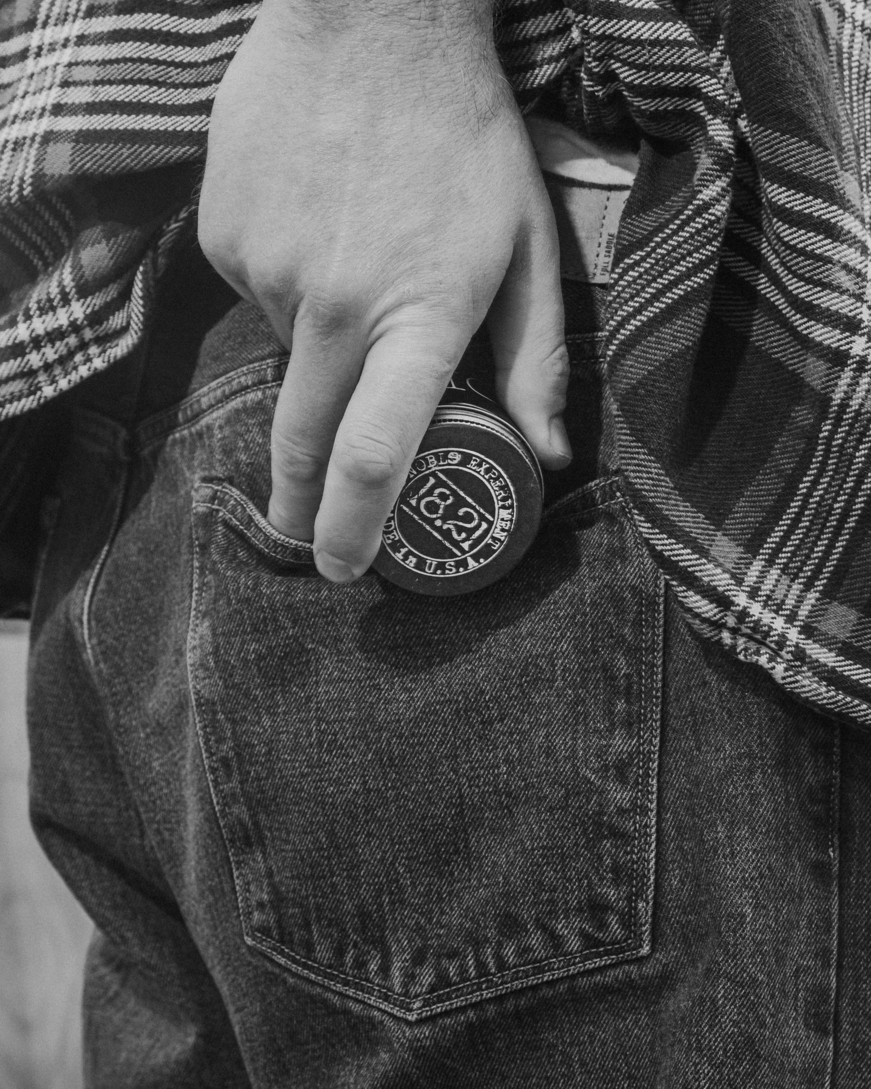 A man putting the 18.21 hair paste in his back pocket