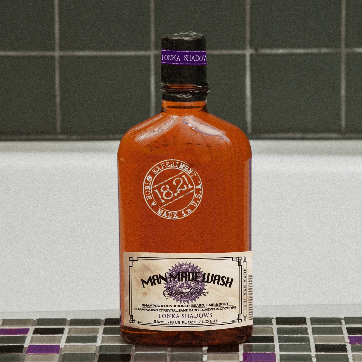 A bottle of Man Made Wash Todka Shadows shown in an amber glass bottle with a purple and white label, set against a tiled background.