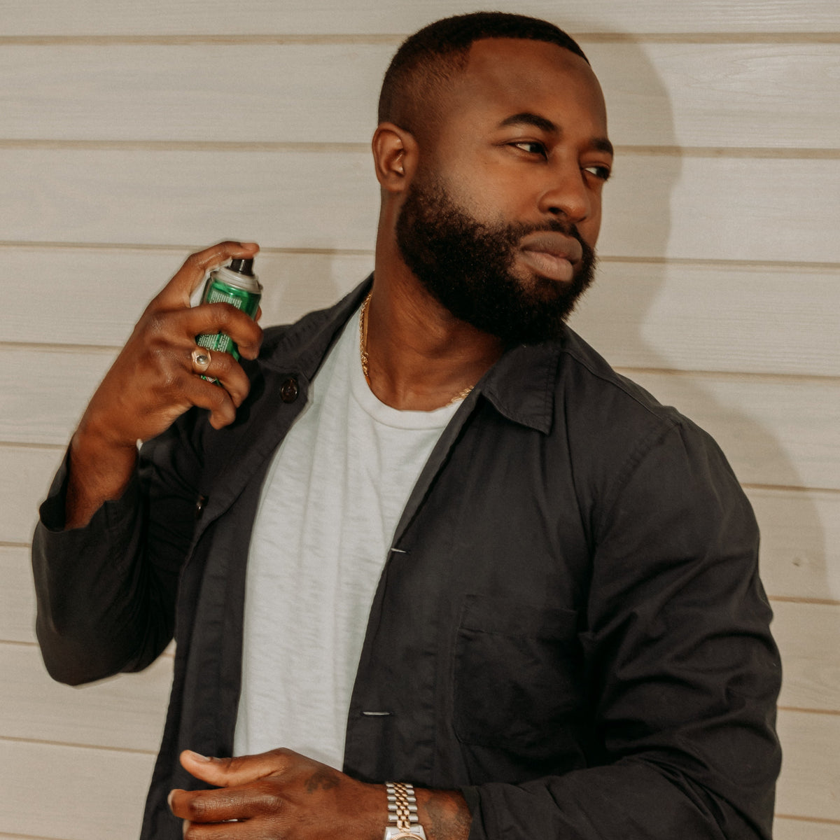 Man holding a can of spray paint against a neutral background