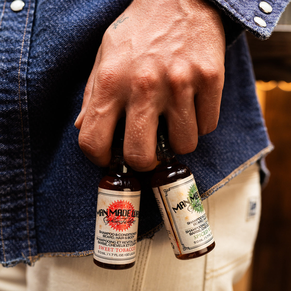 Hand holding two bottles of Man Made Wash travel size