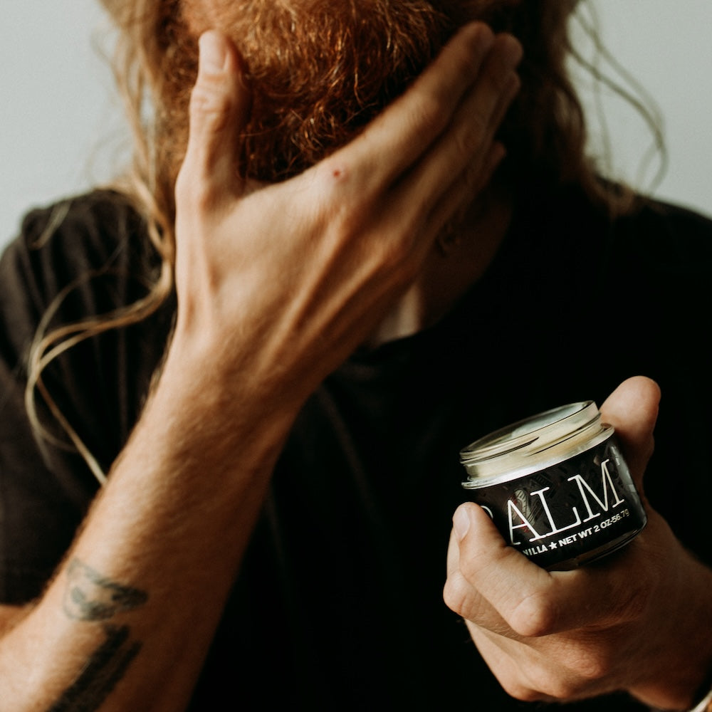Man touching his beard and holding 18.21 Man Made beard balm 
