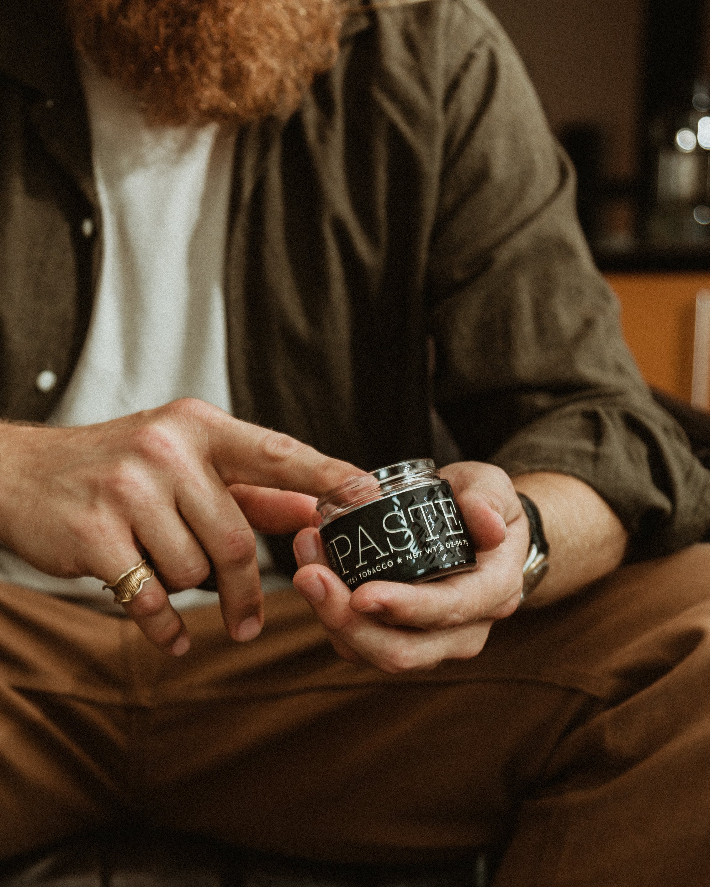 Man holding a jar of  18.21 PASTE product in a casual setting