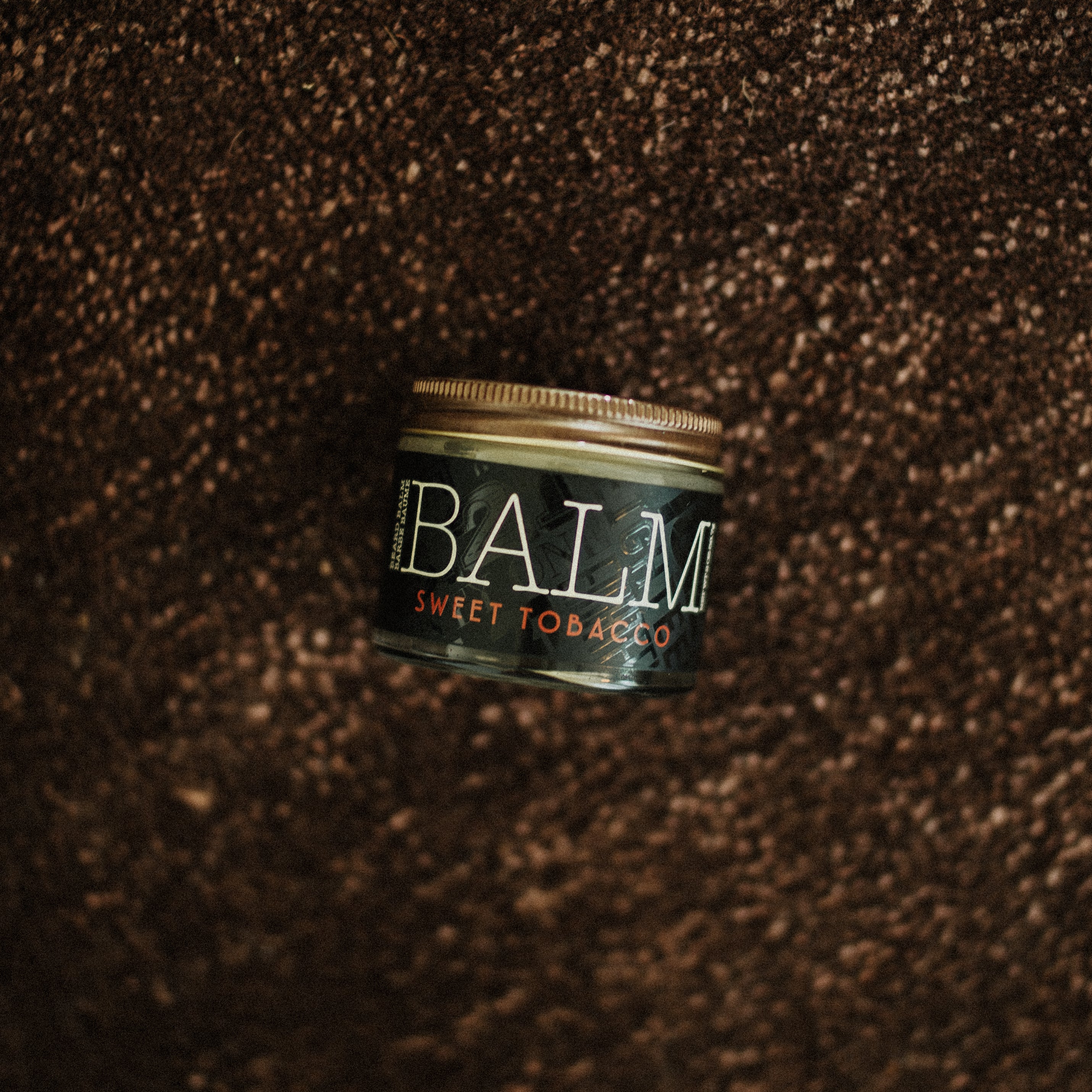Jar of Sweet Tobacco Balm on a textured brown background